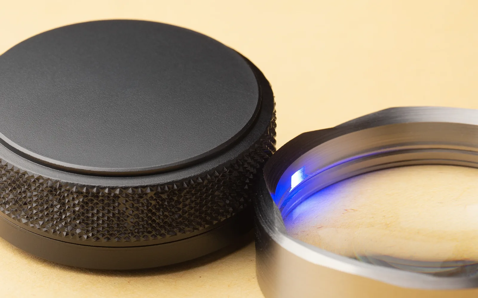 Macro study of precision matte-black aluminum hardware and optical lens with an ultramarine indicator.